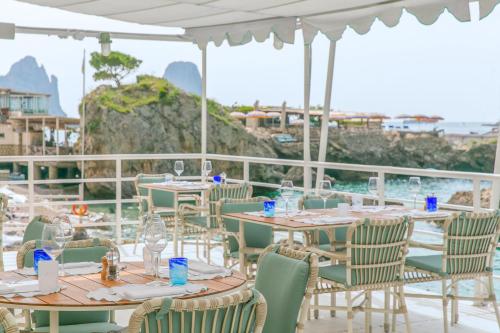a restaurant with tables and chairs with a view of the ocean at Hotel La Palma, Oetker Hotels in Capri