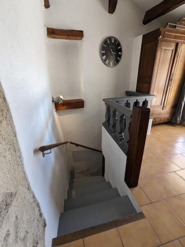 a staircase in a room with a clock on the wall at Maison Porte Saint Croix in Bize-Minervois