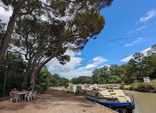 a boat on a river with people sitting at a table at Maison Porte Saint Croix in Bize-Minervois