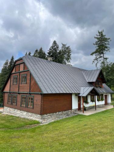 ein großes Holzhaus mit Metalldach in der Unterkunft Třetí chalupa U Smrčiny in Janské Lázně