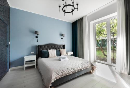 a blue bedroom with a bed and a window at Wiejska Glamour Apartment in Warsaw