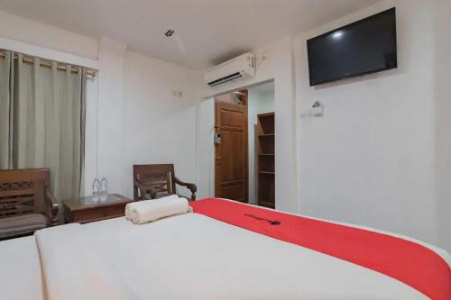 a bedroom with a white bed with a red trim at RedDoorz At Arwiga Hotel in Bandung
