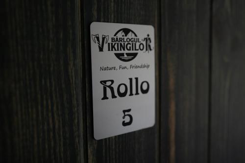 a white sign on a wooden wall with the number three at Bârlogul Vikingilor in Şotrile