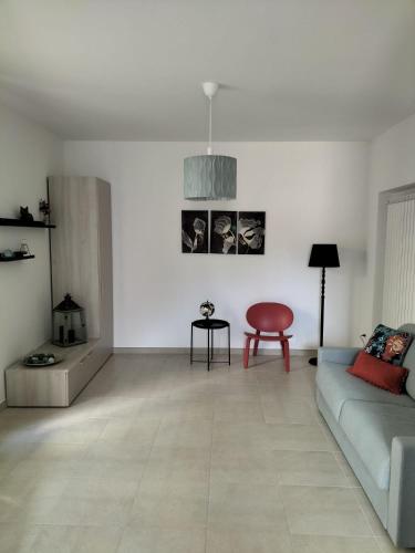 uma sala de estar com um sofá e uma cadeira vermelha em La dimora del Cardinale em LʼAquila