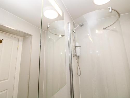een badkamer met een douche en een glazen deur bij Garden Apartment in Buxton