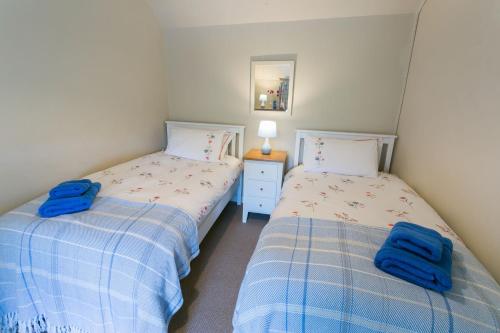 two beds in a bedroom with blue towels at Tyn Lon in Moelfre