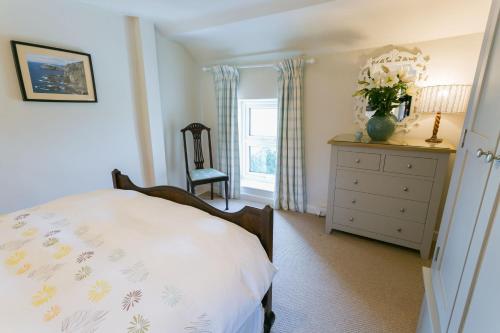 a bedroom with a bed and a dresser and a window at Tyn Lon in Moelfre