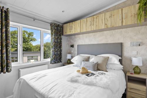 a bedroom with a white bed with a hat on it at Cherry Lodge, 14 Roadford Lake Lodges in Lifton