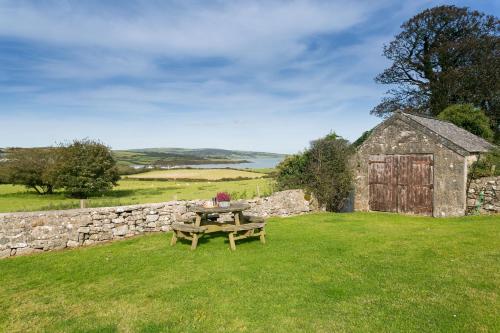 a picnic table in a field next to a stone wall at Tyn Lon in Moelfre
