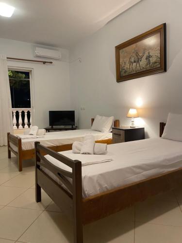 1 dormitorio con 2 camas y TV. en Miranda's Apartments & Rooms en Sarandë