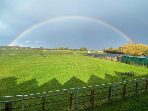 un arco iris sobre un campo verde con una valla en Falabella Suite with amazing views of stud farm., en Great Driffield