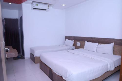 zwei Betten in einem Hotelzimmer mit weißen Laken in der Unterkunft Hotel Kewal INN in Jālgaon