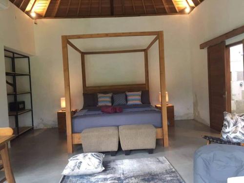 a bedroom with a bed with a wooden frame at Uma Mupu Retreat in Gianyar