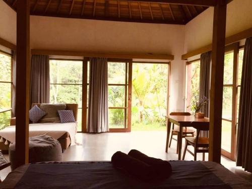 a bedroom with a bed and a desk with a table at Uma Mupu Retreat in Gianyar