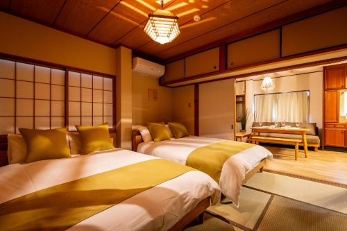 a bedroom with two beds and a bench in it at Chikyuutabikazoku　Kintetsu-Nara Ekimae in Nara