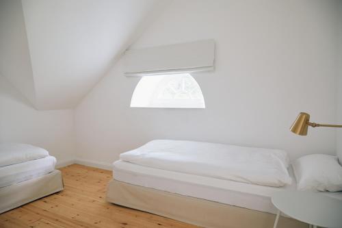 a white bedroom with a bed and a window at Schmiede in Barkelsby