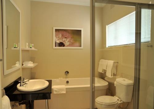 a bathroom with a toilet and a sink and a shower at Cresta Sprayview Victoria Falls in Victoria Falls