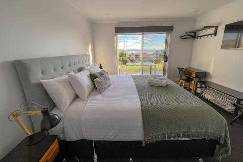 a bedroom with a large bed with a large window at BINALONG BRAE @ Bay of Fires Two bedroom both with ensuites in Binalong Bay