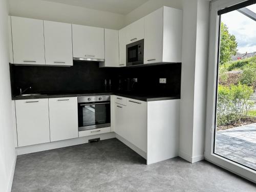 a white kitchen with white cabinets and a window at Apartmány DEER House in Hodkovice nad Mohelkou
