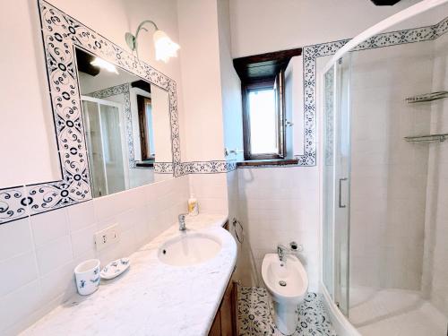 La salle de bains est pourvue d'un lavabo, de toilettes et d'un miroir. dans l'établissement Spoleto Splash Cisternasleeps 23wifiaircon - cute with beautiful garden, à Strettura