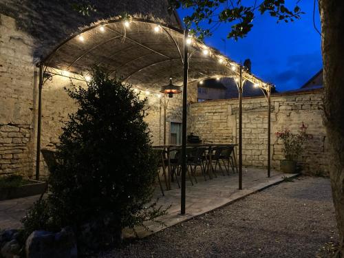 a patio with a table under an arch with lights at Chambres Privées des HAMY au coeur du parc national ENTRÉE AUTONOME in Arc-en-Barrois
