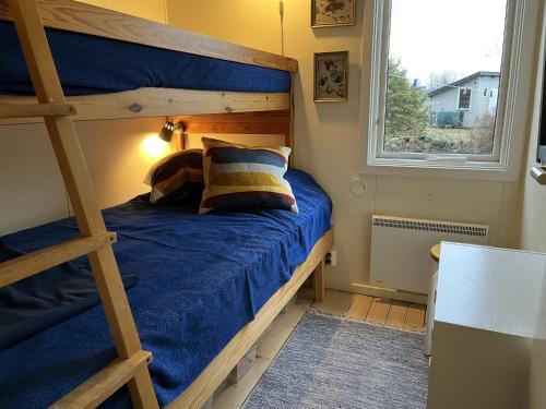 - une chambre avec des lits superposés avec des draps bleus et une fenêtre dans l'établissement Nice cottage located in the north of Oland next to Byxelkrok, à Byxelkrok