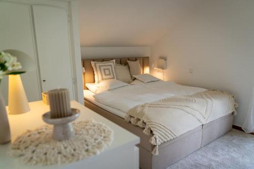 a white bedroom with a bed and a table at Eifel21 - stilvolles Haus in der Vulkaneifel in Bleckhausen
