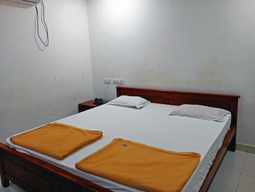 a bedroom with a bed with white sheets and orange sheets at STAYMAKER Shri Shakti Residency in Hubli