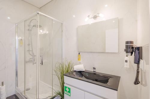 uma casa de banho com uma cabina de duche em vidro e um lavatório. em Feel Porto Historical Apartments no Porto