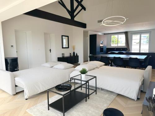 uma sala de estar com duas camas e uma mesa em Les appartements du Carnot - Terrasses et Jardins em La Rochelle