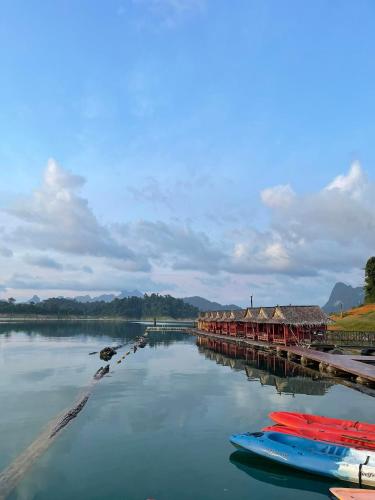 a river with houses and boats in the water at Khao Sok Green Mountain View in Khao Sok