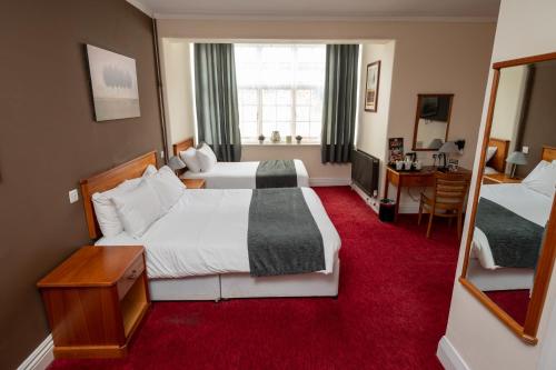 a hotel room with two beds and a mirror at Bridge Inn by Greene King Inns in Port Sunlight