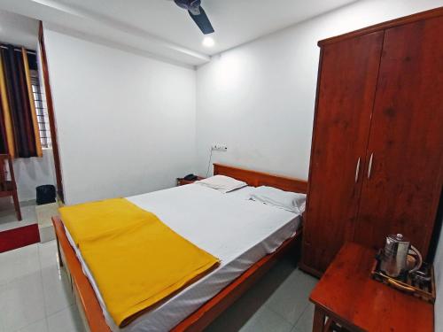 a bedroom with a bed and a wooden cabinet at STAYMAKER Shri Shakti Residency in Hubli