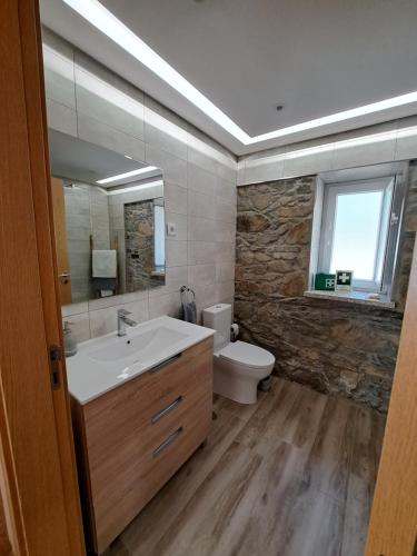 a bathroom with a sink and a toilet and a mirror at A Casa dos Avós - Alojamento Local in Sertã