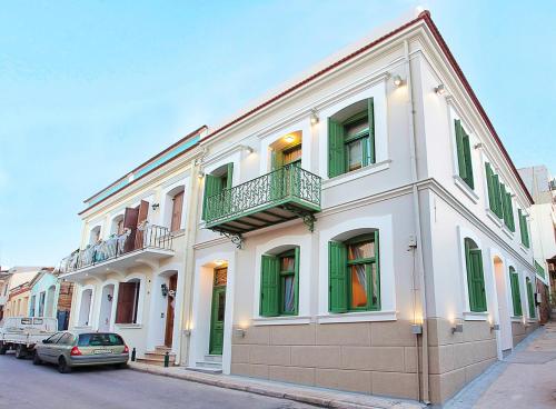 een wit gebouw met groene ramen en een balkon bij Atsiki's 54 apartments in Chios