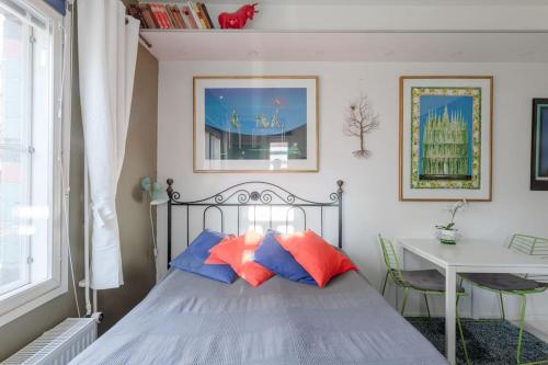 1 dormitorio con 1 cama con almohadas azules y rojas en Studio - nearby centrum & metro, en Helsinki