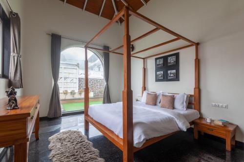 1 dormitorio con cama con dosel y ventana grande en Lake Arches by StayVista - Lakeside villa with Infinity pool, Gazebo & Modern Greek interiors, en Igatpuri