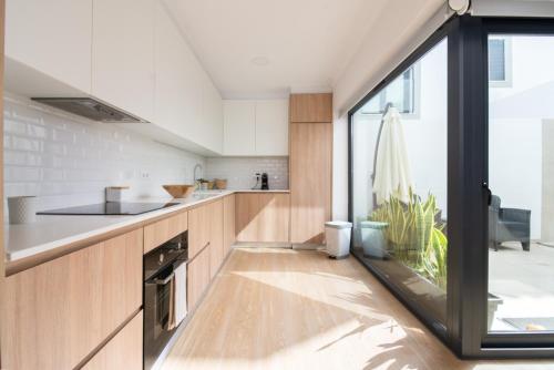 a kitchen with wooden cabinets and a large window at PÉ NA AREIA II by Stay in Alentejo in Vila Nova de Milfontes