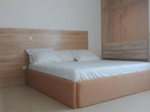 a large bed in a bedroom with a wooden headboard at Appartments Meuble SEED in Yaoundé