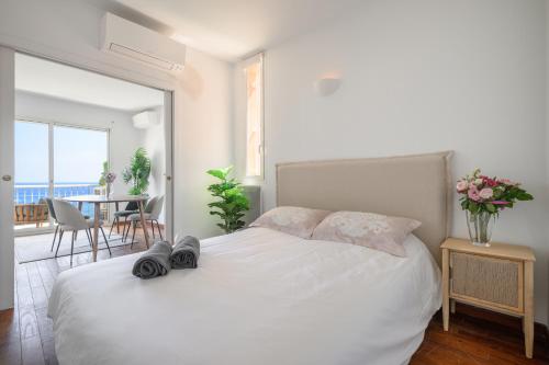 a bedroom with a white bed and a table with chairs at Proche Monaco, vue mer et accès à la plage in Saint-Antoine