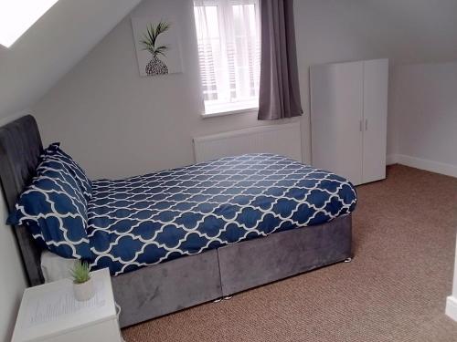 a bedroom with a bed with a blue comforter and a window at Cosy & Spacious 4 Bedroom House with Free Parking in Birmingham 