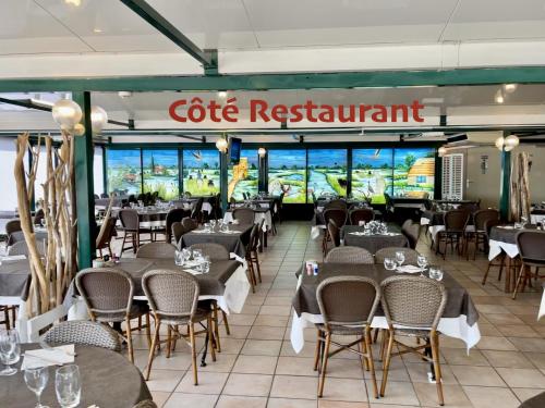 un restaurant avec des tables et des chaises et un panneau indiquant « restaurant de golf » dans l'établissement Hotel Restaurant La Ceinture, à Montcalm