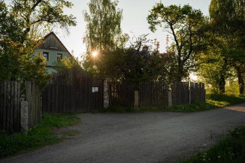 a fence in front of a house with the sun behind it at Apartmány Penzion Kateřina in Nadějkov