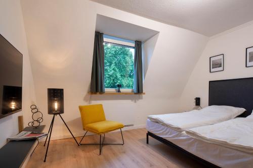 a bedroom with a bed and a yellow chair at Renoviertes Design Apartment mit Toller Terasse in Mülheim an der Ruhr