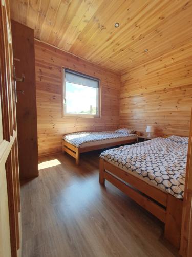 a room with two beds in a wooden cabin at Domki LENA Bobolin in Bobolin
