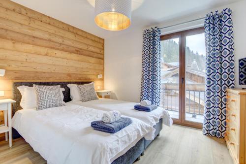 um quarto com 2 camas e uma grande janela em Le Major Apartment em Morzine