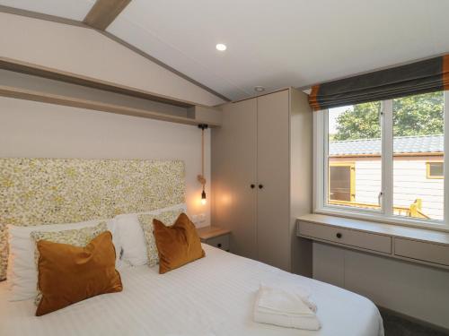 a bedroom with a large white bed with a window at Lodge 9 in Winscombe