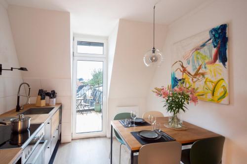 een keuken met een tafel met een vaas met bloemen erop bij Renoviertes Design Apartment mit Toller Terasse in Mülheim an der Ruhr