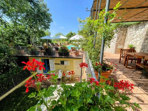 a patio with red flowers and tables and umbrellas at Torretta sleeps 5 with pool and exclusive gardens plus private verandah in Strettura
