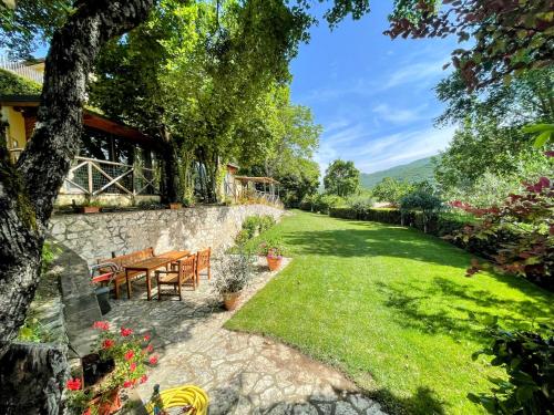 a garden with a table and chairs and a stone wall at Torretta sleeps 5 with pool and exclusive gardens plus private verandah in Strettura